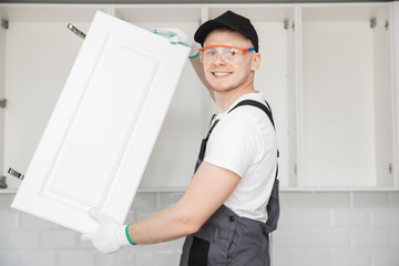 Kitchen installation, worker fixing door cabinet front assembling furniture white carved