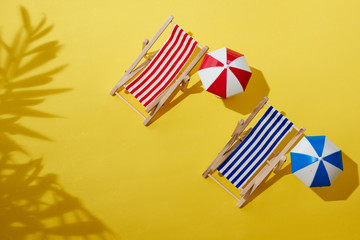 Beach chairs with yellow background and shadow of a tree.
