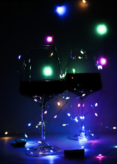 two glasses of red wine at a party with blue garlands
