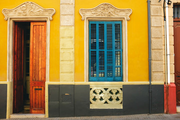 a beautiful colourful yellow building with blue shutters. The perfect mediterranean style home that is bright and inviting when traveling around Europe. Perfect European home. 