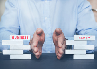 Businessman separating wooden blocks with the inscription Business and Family.
Choice between...