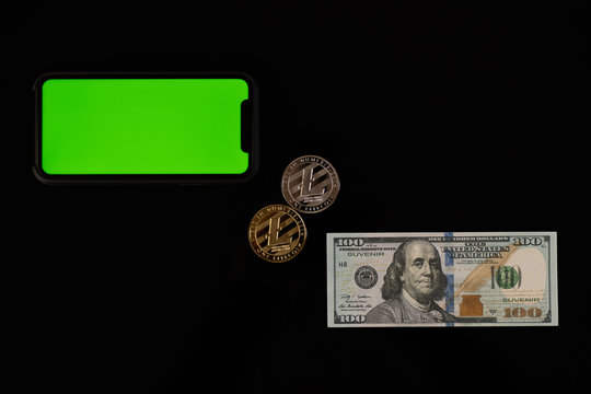 Phone with green screen, dollar bill and litcoin coins isolated on black background