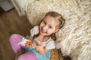 little girl sitting on floor leaning on sofa and fun playing with finger toys
