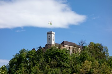 Clock tower of Ljubljana Castle in Slovenia at the summit of the hill hidden behind trees