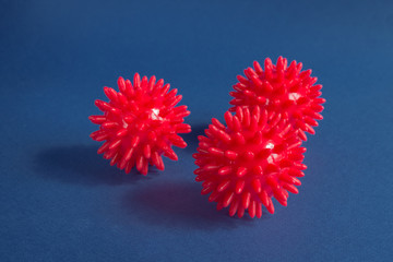 Red studded massage balls on a blue background. Abstract model of a strain of the virus of the coronavirus disease COVID-19.