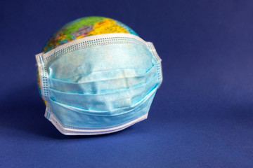 Blue protective medical disposable mask on a globe. The concept of coronavirus and pandemic danger...