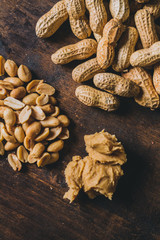 Peanuts in many ways: peeled, shelled and in peanut butter on a rustic wooden table
