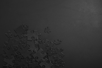 small and large black puzzles randomly scattered on a dark background with space for your text