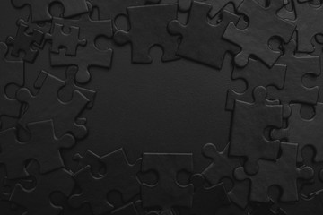 black puzzles randomly folded into a shape that forms a frame with space for your text on a dark background