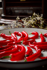 Red hot chilli peppers in a white tray on wooden background. Spicy food.