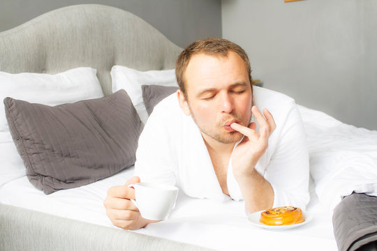 A Man Is Eating Food In Bed. The Guy Licks His Fingers For Food With His Eyes Closed. Tasty Breakfast. Real Jam.