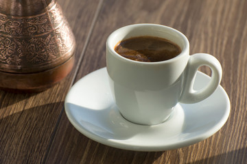A cup of freshly brewed expresso coffee in a Turk is on the table. Drink coffee in the early morning.