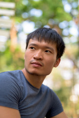 Portrait of young Asian man thinking at the park outdoors