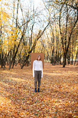 Young model demonstrating autumn collection piece standing with piece of carton behind 