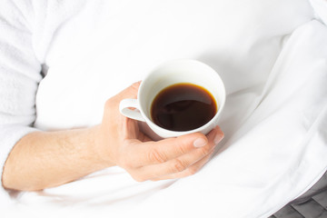 Cup with coffee in the men's hands. Morning coffee for a man. A cup of tea in male hands on a white background.