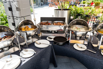 Live food stations in the line. Buffet Table with Row of Food Service Steam Pans, grilled meat and chops