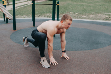 A young guy stretches and warms up on the sports ground.
