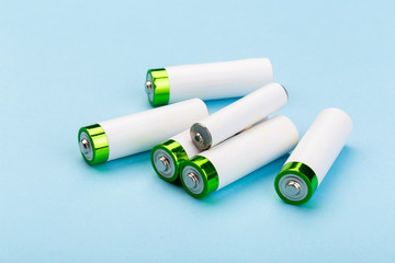 many new and used batteries of different shapes, AA, round batteries on a blue background.