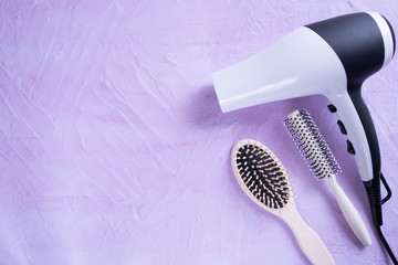 white hair dryer and two combs lie on a white texture