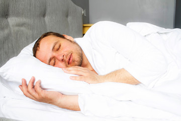 Photo of a handsome sleeping young man. A blond man is sleeping in a white bed. The sleep of a man.
