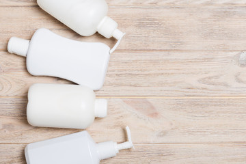 Set of White Cosmetic containers on wooden background, top view with copy space. Group of plastic bodycare bottle containers with empty space for you design