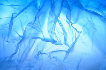 Abstract background of folds of thin plastic, gradient blue color.