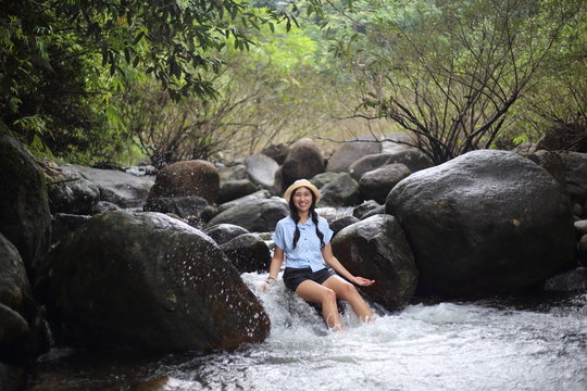 Woman sitting on a rock at Trok Nong Waterfall in Chanthaburi, Thailand