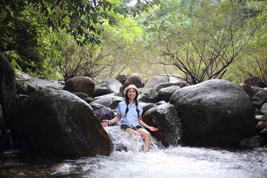 Woman sitting on a rock at Trok Nong Waterfall in Chanthaburi, Thailand