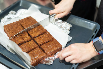 Woman cutting brownie cake into little pieces