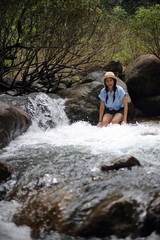 Woman sitting on a rock at Trok Nong Waterfall in Chanthaburi, Thailand