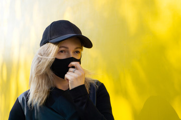 Woman with black protective and medicine mask on yellow background against influenza virus and during pandemic infection. Pandemic coronavirus 2020 and Quarantine. Stop the virus and epidemic diseases