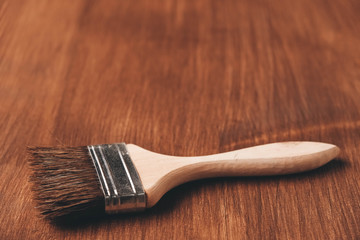 Brush with wooden handle and natural bristles against the background of painted brown wooden...