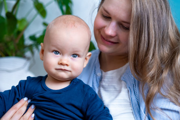 Happy baby. Little cutest chubby caucasian white infant child looking and smiling at camera on mother hands. Family life, moms love, motherhood.