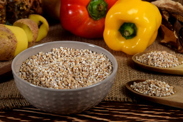 yellow and red raw peppers, dried plums next to potatoes and barley groats and dried mushrooms