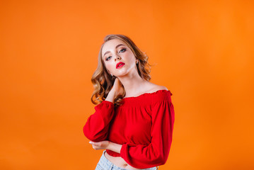 A young beautiful girl shows emotions and smiles in the Studio on an orange background. Girls for advertising