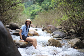 Woman sitting on a rock at Trok Nong Waterfall in Chanthaburi, Thailand