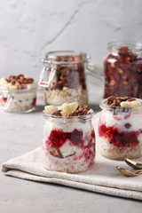 Oatmeal, granola with berries, strawberry chips, cottage cheese and natural yogurt, a delicious and healthy breakfast, located in glass jars on a gray background, Closeup