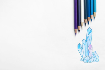Drawing of crystals and colorful pencils on white background, top view