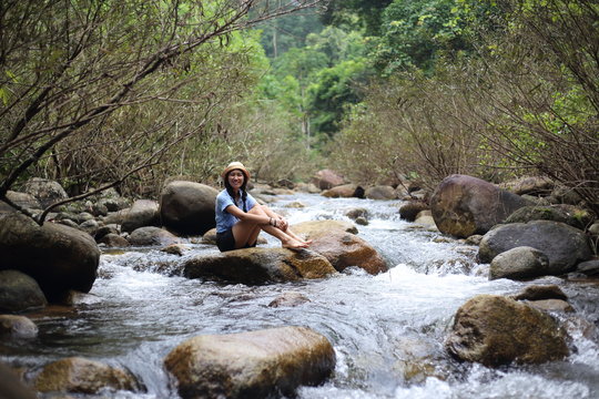Woman sitting on a rock at Trok Nong Waterfall in Chanthaburi, Thailand