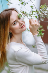 A smiling girl in a white blouse stands in a cherry blossom