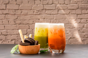 Green tea and Iced milk tea with dessert on white brick wall Background.