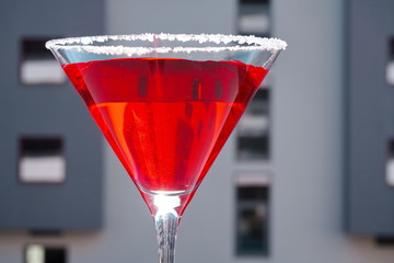 Red cocktail in a Martini glass on a gray background. Red liquid in a glass. Glass beaker.