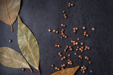 Spices on a black background - bay leaves and coriander