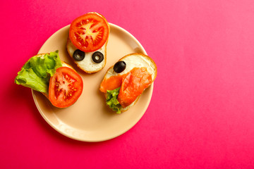 Assorted sandwiches set on a white plate on a pink background.