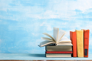 Composition with vintage old hardback books, diary, fanned pages on wooden deck table and abstract background. Books stacking. Back to school. Copy Space. Education background.