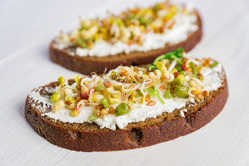 Healthy macrobiotic breakfast. Sandwich with cream cheese, peas microgreens and sprouted mung beans, walnut, sunflower and flax on wooden background. vegan, raw food diet.