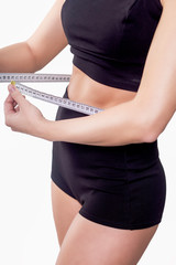 girl in a fitness suit measures the waist with a centimeter on a white background