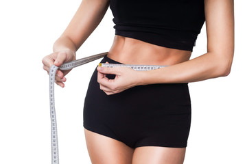 girl in a fitness suit measures the waist with a centimeter on a white background