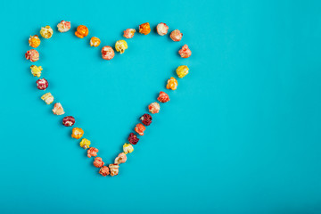 Heart laid out of corn kernels on a blue background.