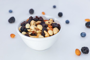 Nuts and berries are scattered on the table. nuts are in the plate.